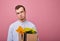 Fired sad pretty guy in glasses stands on a pink background with a cardboard box with different things