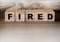 Fired written on a wooden cubes on red. Crisis, career, business concept