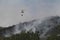 Firefight helicopter dropping water over fire on a forest