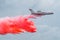 Firefighter airplane drops red water on a fire in the forest.