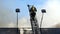 A firefighter climbs a high metallic staircase with forks of flame under him.