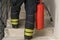 A firefighter climbs the stairs and carries a red fire extinguisher