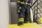 A firefighter descends the stairs and carries a hose line and equipment for extinguishing fires indoors, front view