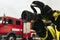 Firefighter on duty with water hose in front of fire truck ready for extinguishing. Close-up