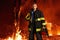 Firefighter with sad equipment, holds the helmet in his hand, which stands against the background of a forest in flames.