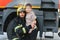 A firefighter take a little child boy to save him. Fire engine car on background