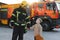 A firefighter take a little child boy to save him. Fire engine car on background