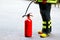 Firefighter wearing uniform and standing beside red extinguisher