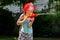 Firefighter, young child, little school age girl wearing a fireman helmet playing with a water gun in the garden. Dreams