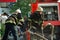 Firefighters connect hoses to a hydrant on the street near a burning building. Extinguishing a burning building