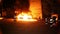 Firefighters extinguish burning cars at night