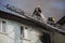 Firefighters on ladders in oxygen masks extinguish the fire in an old house in the middle of the city