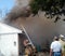 Firefighters watches as sFirefighters watches smoke pours out from a house