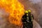 Firefighters wearing fire fighter suit for safety and using twirl water extinguisher for fighting the fire flame in emergency