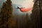 firefighting aircraft flies over forest, dropping fire retardant