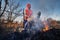 Fireman ecologist fighting fire in field in the evening