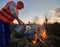 Fireman ecologist fighting fire in field in the evening