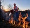 Fireman ecologist fighting fire in field in the evening