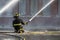 A fireman kneels in the middle of wet, icy road.