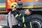 A fireman shows his work to his young son. A boy in a firefighter& x27;s helmet