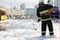 Fireman standing among firefighting foam and carrying fire hose reel