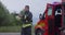 fireman using walkie talkie at rescue action fire truck and fireman\'s team in background.