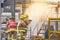 Firemans in yellow fire fighter uniform holding fire hose nozzle spraying foam water control fighting