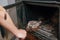 Fireplace cleaning. A woman\'s hand holds a shovel with ash in a burnt-out fireplace. Close up view