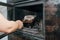 Fireplace cleaning. A woman\'s hand holds a shovel with ash in a burnt-out fireplace. Close up view