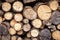 Firewood pile, pattern with ends of logs close-up. Woodpile of brown timber, stack of rough sawn trees with bark