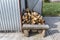 A firewood stacked in a pile, lying on the property near the metal garage, wooden background.