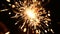 Firework sparkler burning isolated from top to bottom in macro shot. Gun powder sparks shot against deep dark background