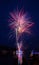 Fireworks with red and blue colors launched from a river barge