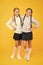 Firm friends. School girls with plaited hair in long braids. Cute little girls smiling on yellow background. Happy small