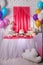 First baby girl birthday party concept. Candy bar with sweet unicorn cakes and decor items in bright pink colors.