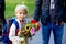 First day at school for a firstgraden, child starting school, bringing flowers for the teacher, family going with him