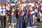 First-form schoolgirl at school on holiday of beginning of elementary education reading poetry. Girl with microphone declaiming