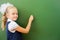 First grade schoolgirl wrote on blackboard with chalk at classroom