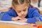 First grader to read lesson reads the text in the book with his head in his hands