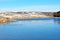 First ice on lake, withered reeds and hills with autumn yellow grass under snow and forest