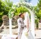 First kiss of newly married couple under wedding arch