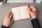 First person top view photo of female hands holding pencil over red open organizer white keyboard mouse and cup of coffee on