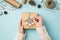 First person top view photo of female hands in sweater decorating giftbox with snow twig over balls scissors spool of twine roll