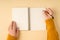 First person top view photo of female hands in yellow knitted sweater writing in spiral notebook on isolated pastel orange