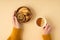 First person top view photo of female hands in yellow sweater holding cup of tea with lemon and wooden bowl with cookies dried