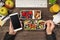 First person top view photo of hands eating healthy food from lunchboxes and holding cellphone apples glass of juice plant