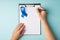 First person top view photo of hands holding pen and clipboard with paper sheet and blue ribbon symbol of prostate cancer