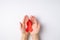 First person top view photo of hands holding red ribbon in palms symbol of aids awareness on  white background with