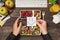 First person top view photo of hands holding sticky note with drawn smiling face over lunchboxes with healthy food apples glass of