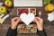 First person top view photo of hands holding white paper heart over lunchboxes with healthy food glass of juice plant stationery